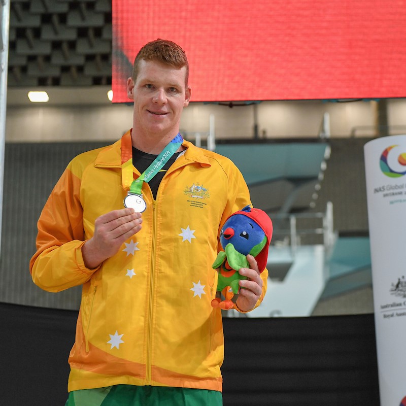 Male Paralympian Liam Schluter with medal and mascot