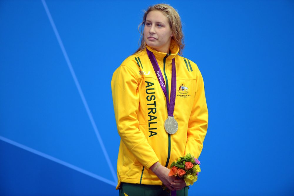 Para-swimmer Taylor Corry standing with her silver medal. Wearing green and gold Australia Para-Athlete atire.