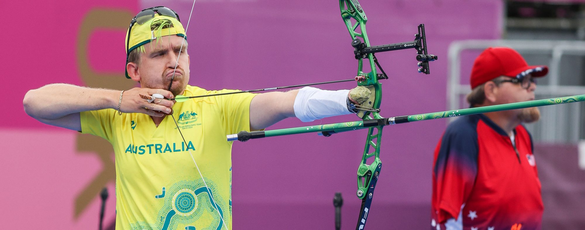 A male Australian Para-archer lining up to take a shot to the left of the image