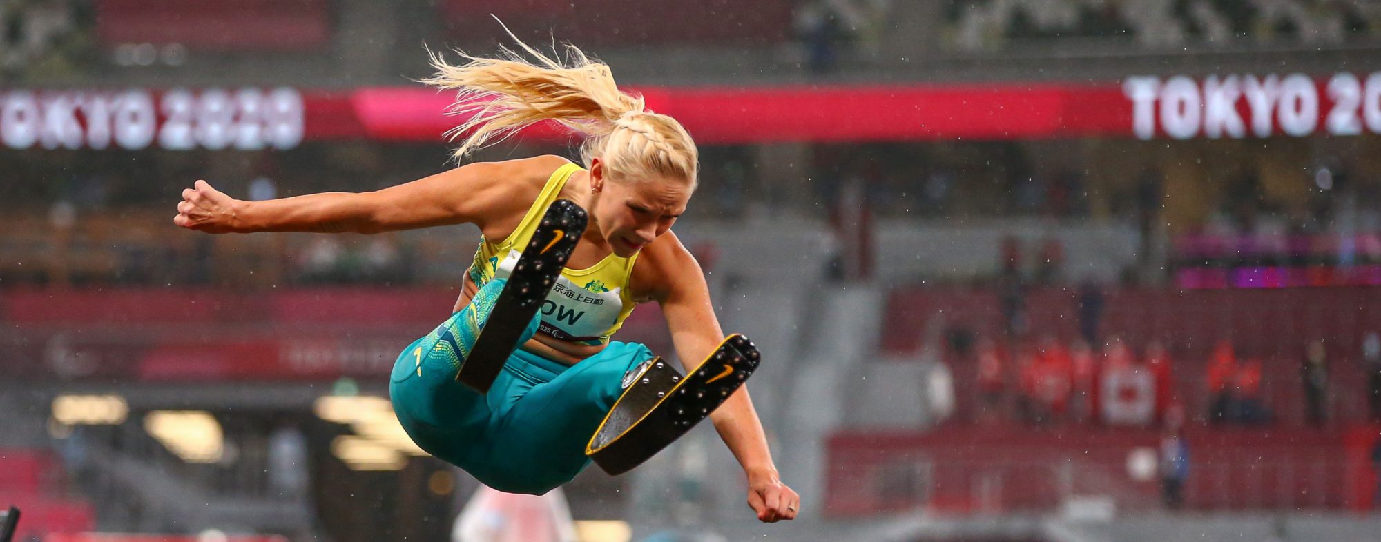 A female Australian long jumper with blonde hair jumping in the air