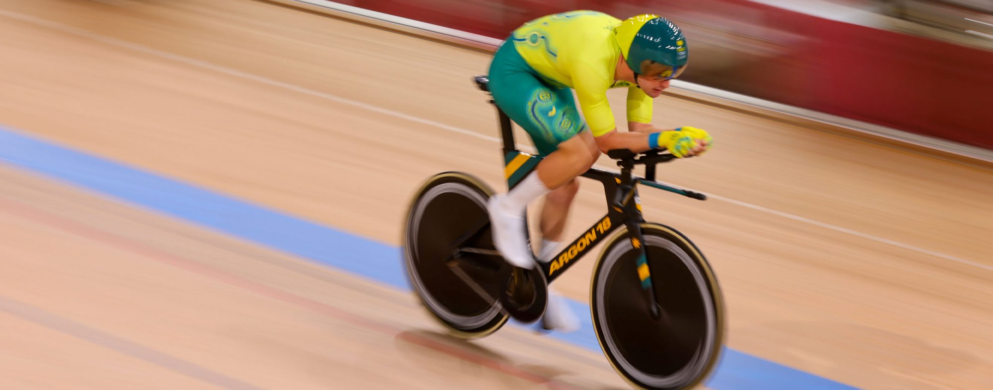 A male Australian Para-cyclist riding on the Velodrome track in Tokyo.