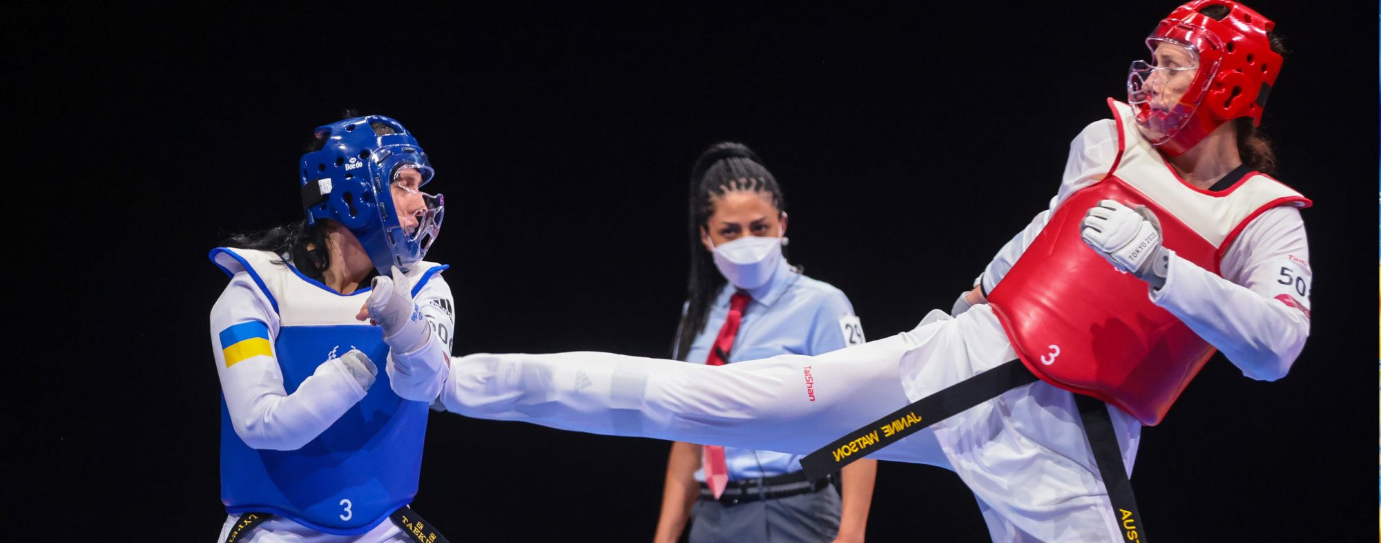 A female Para-taekwondo athlete in red kicking a female Para-taekwondo athlete in blue