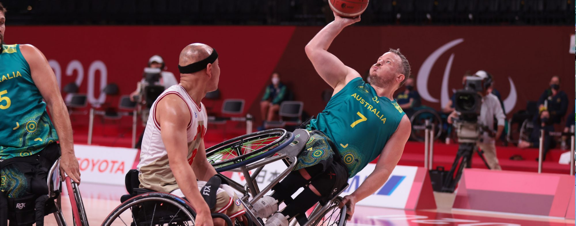 A male Australian Wheelchair basketball player taking a shot while falling