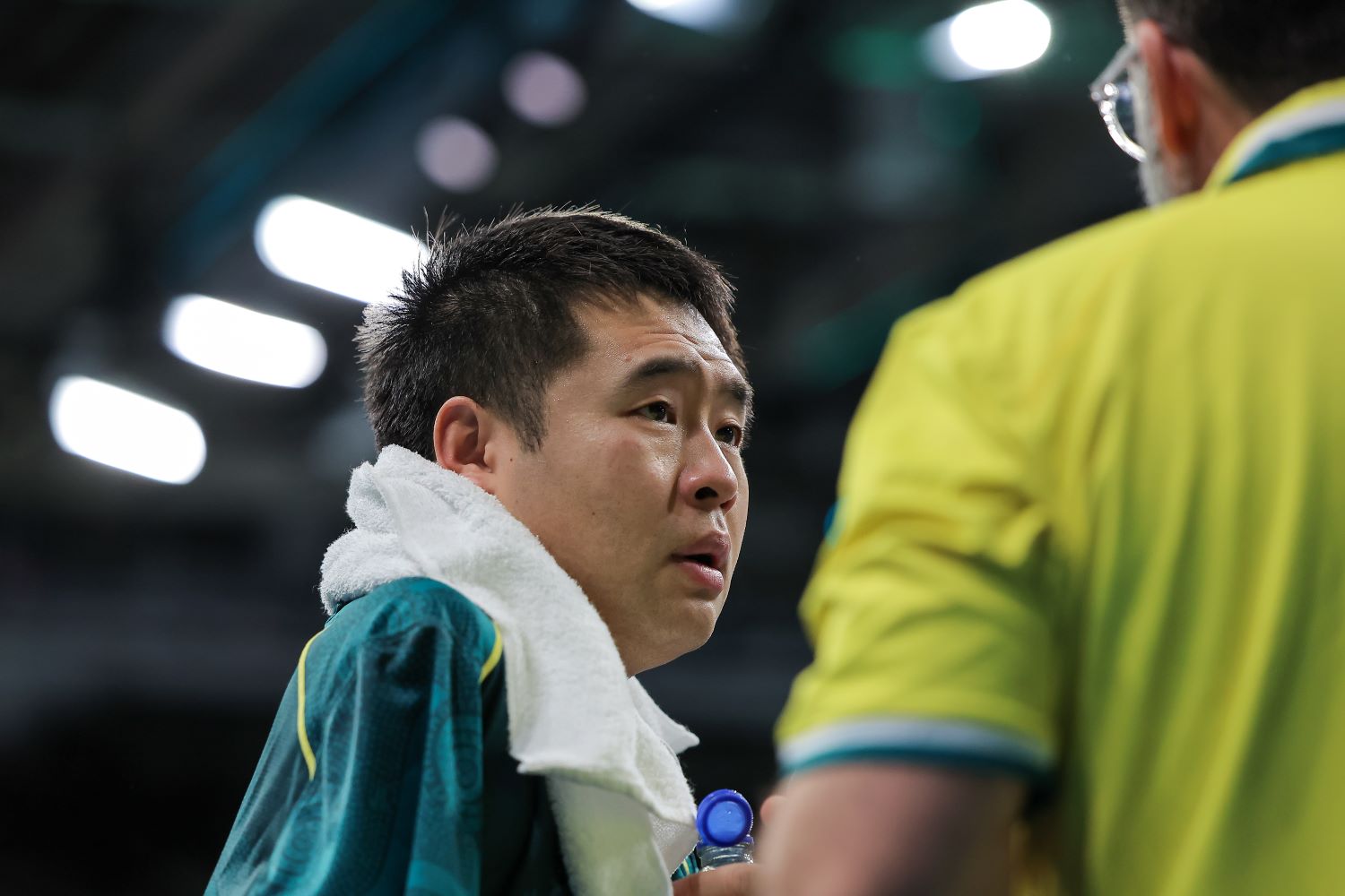 Para-table tennis player Lin Ma talks to his coach with a towel around his neck.